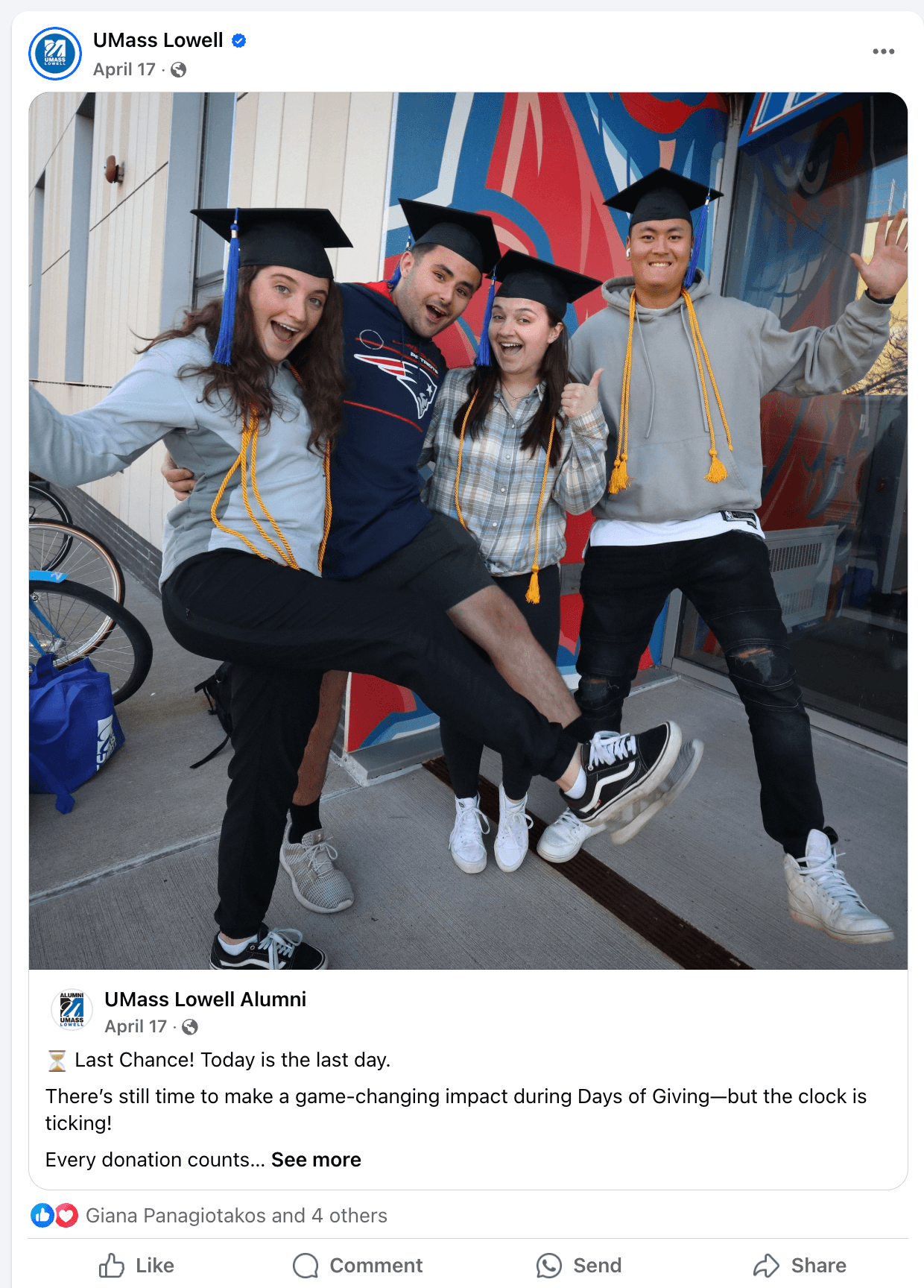 Four UMass Lowell students in graduation caps and cords celebrating outside a campus building.